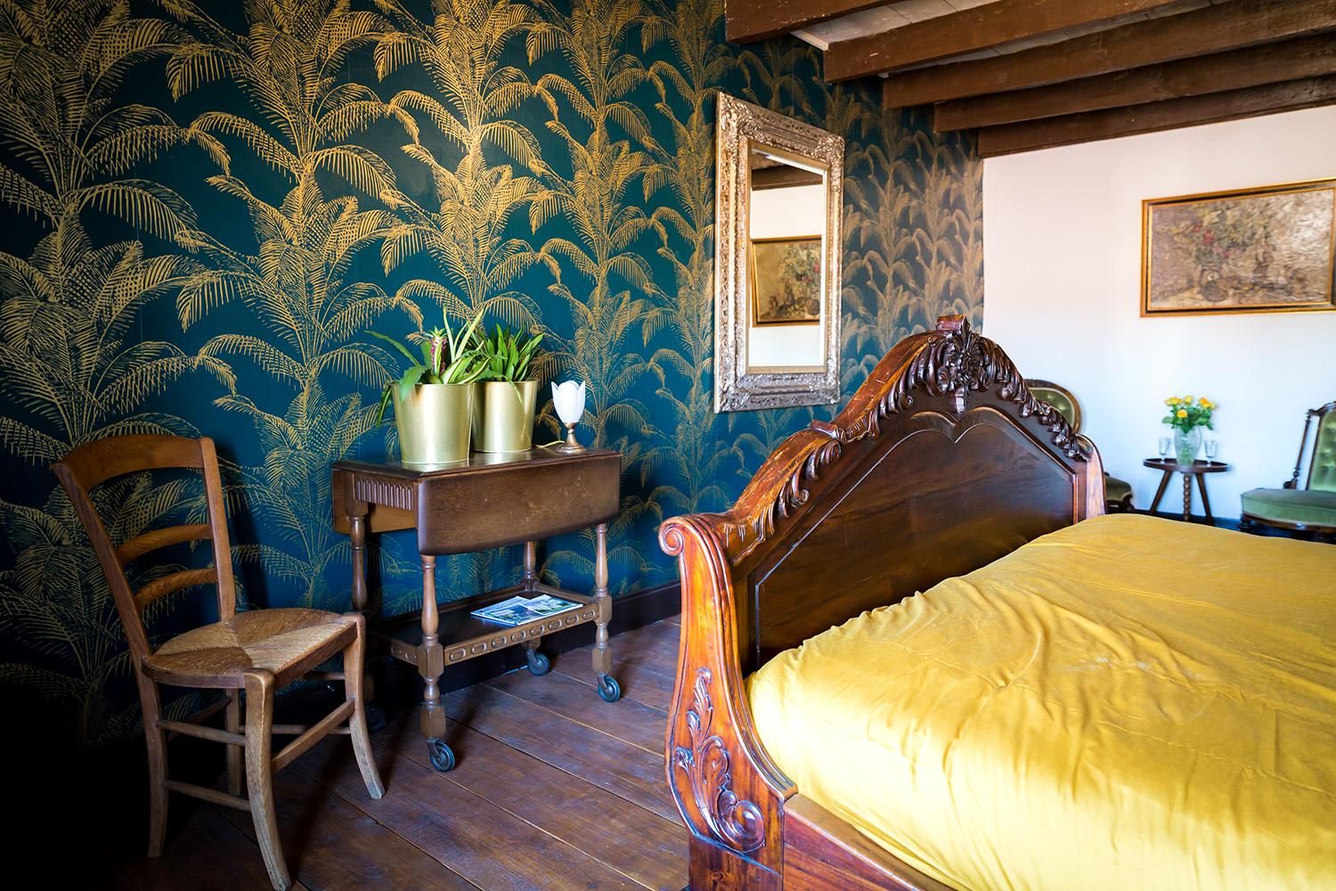De slaapkamer met antiek bed en palmbehang
